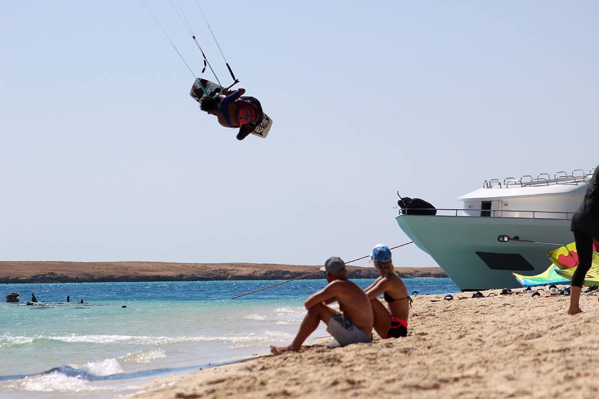 Kiters relaxing on the beach watching another kitesurfer practcing his tricks!