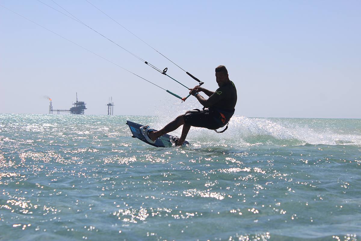 Kite surfer in the red sea with oil rig in the back ground.